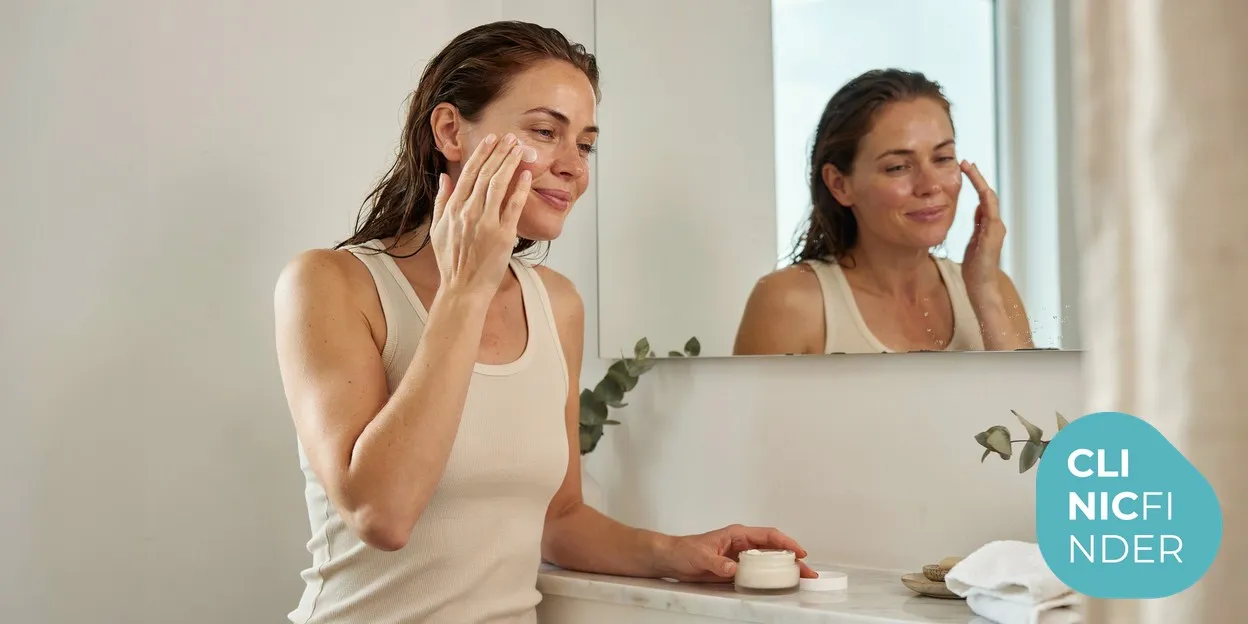 A woman gently smoothing fragrance-free moisturiser onto her cheek in soft daylight, part of everyday rosacea skincare